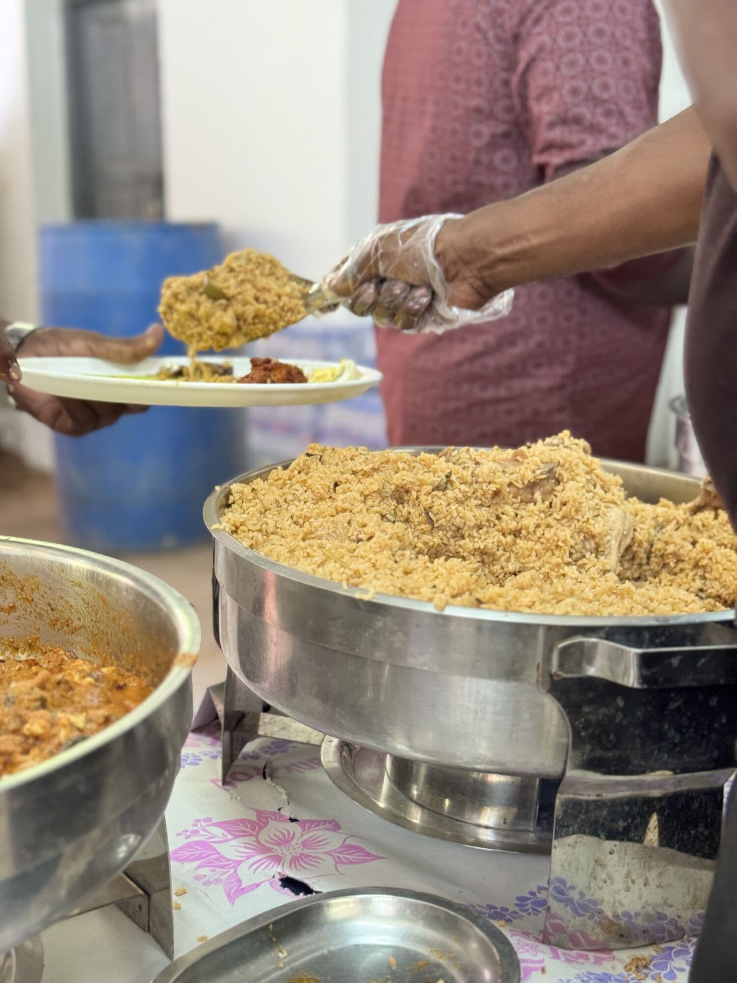 An SDR server ladling biryani onto a guest's plate