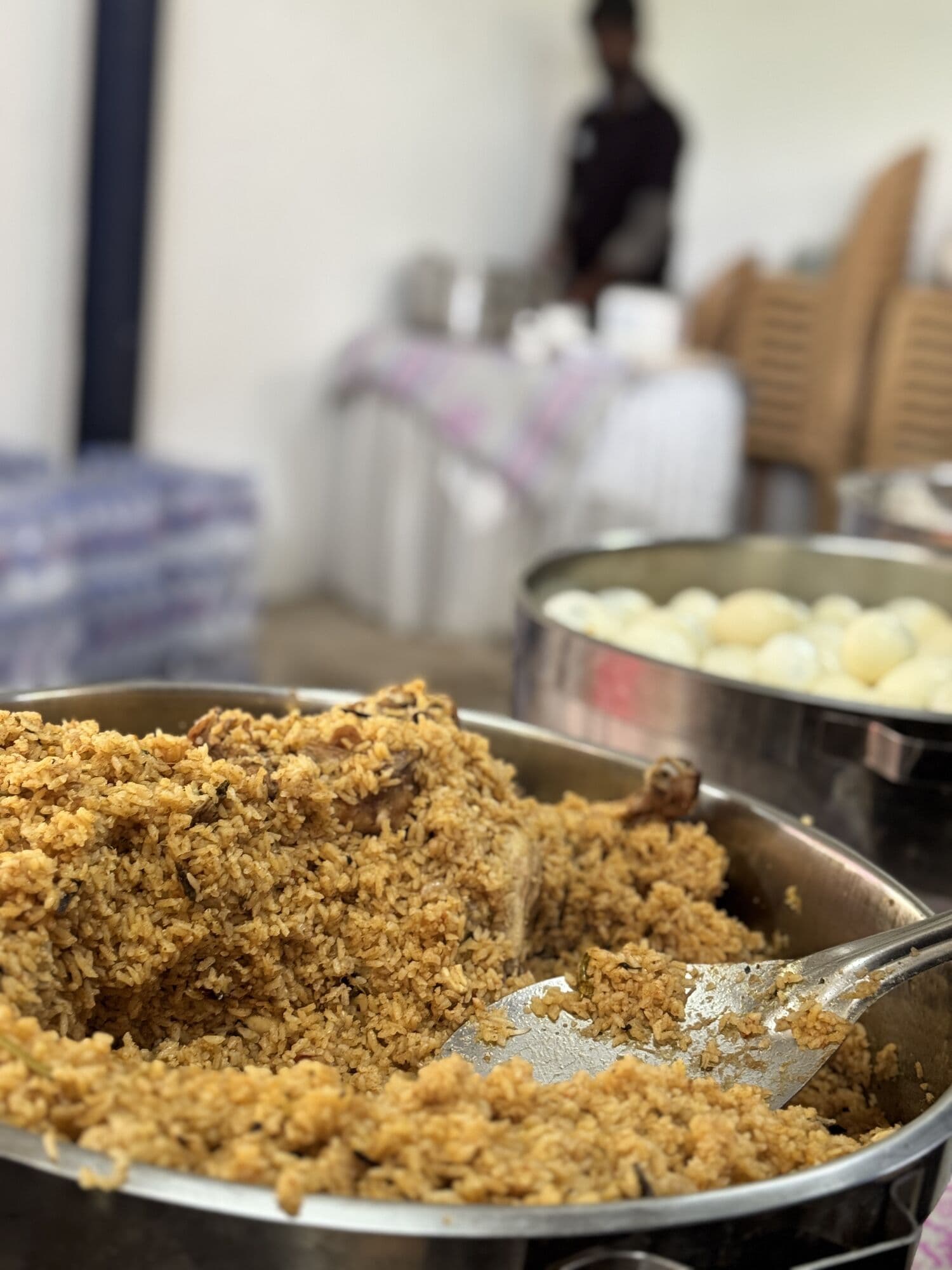 A large tray of biryani beside a pan of boiled eggs
