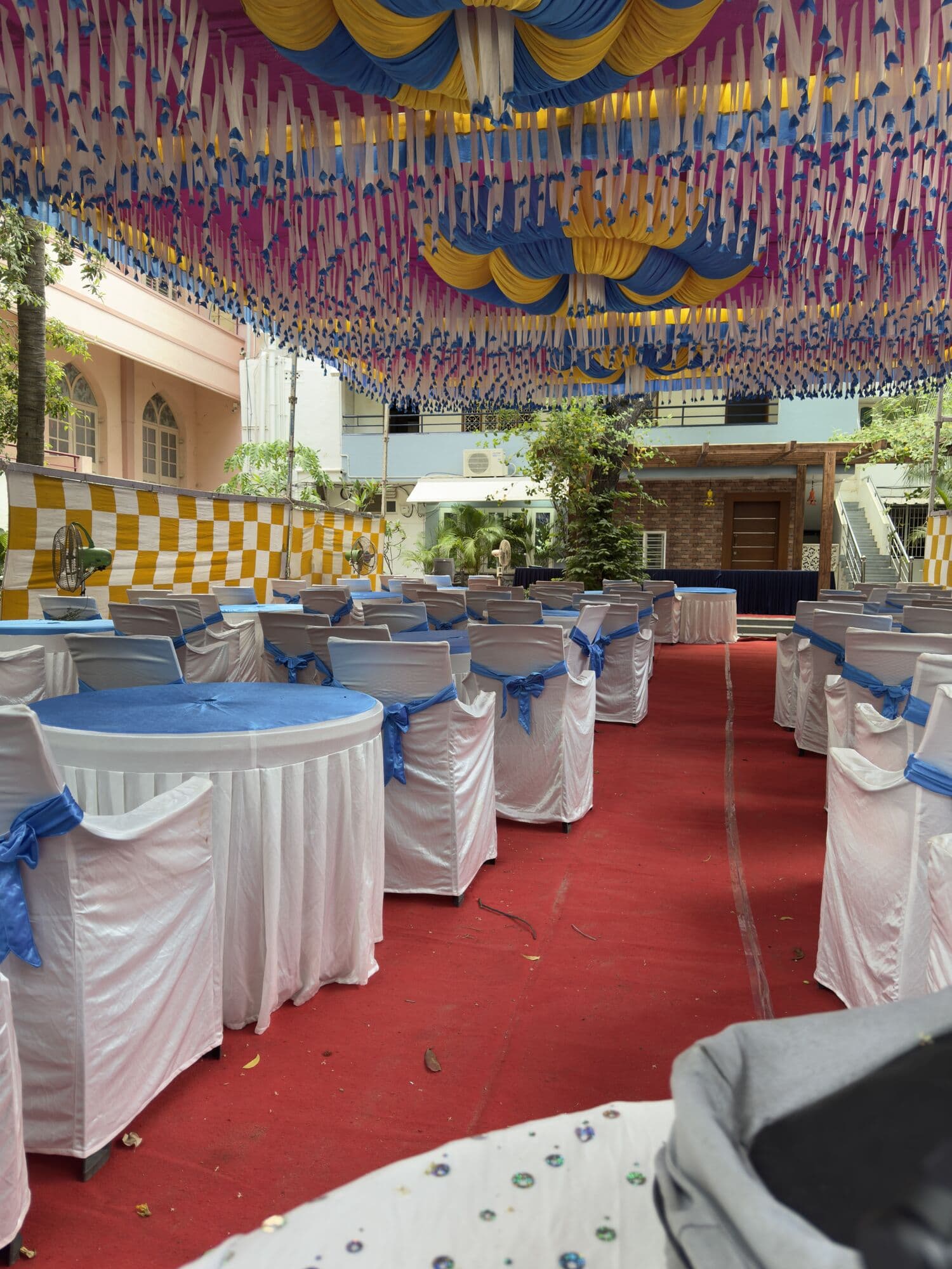 A decorated event venue with draped chairs under a ribbon canopy